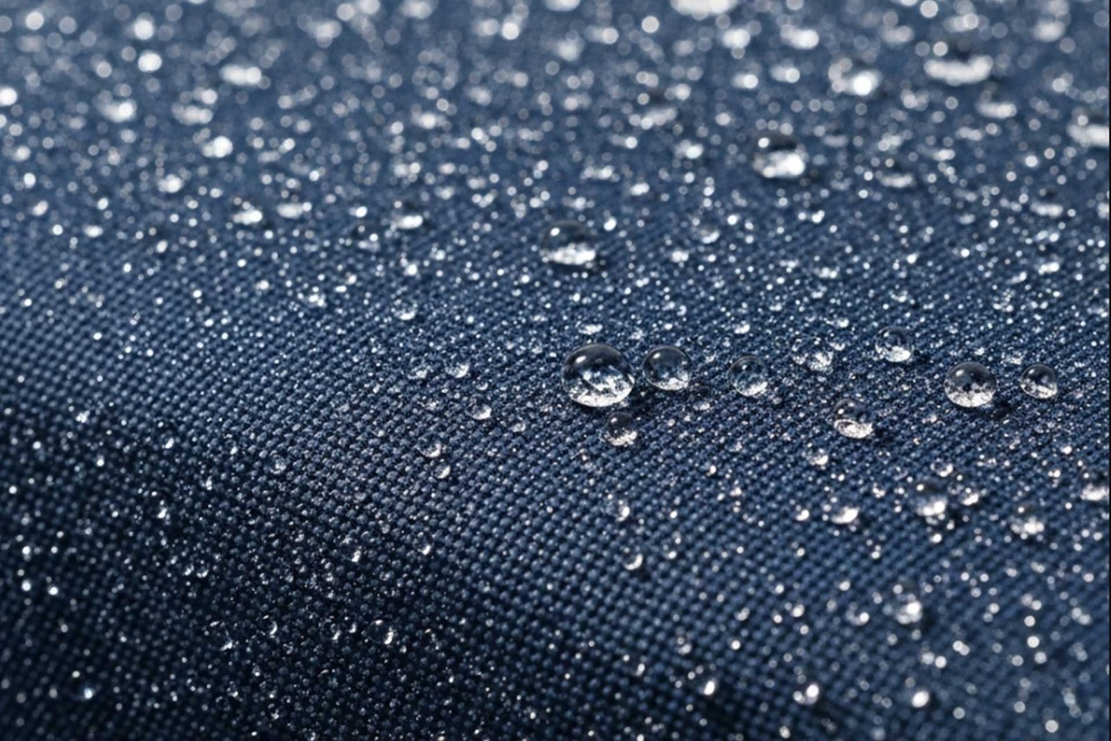 A water droplet beading up on a textured polyester upholstery swatch